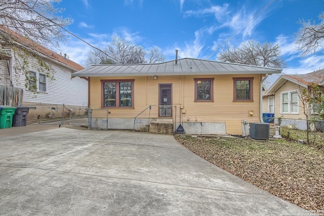 view of front of property featuring a standing seam roof, fence, central AC unit, and metal roof