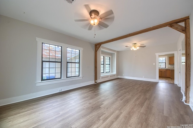 spare room with a ceiling fan, light wood-style floors, and baseboards