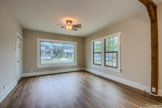 spare room featuring a ceiling fan, visible vents, baseboards, and wood finished floors