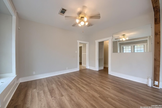 unfurnished room featuring a ceiling fan, visible vents, baseboards, and wood finished floors