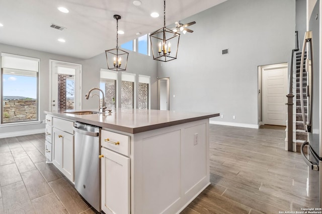 kitchen with ceiling fan, appliances with stainless steel finishes, a kitchen island with sink, pendant lighting, and white cabinets