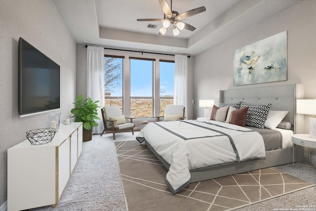 bedroom featuring ceiling fan, carpet, and a tray ceiling