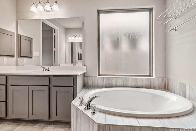 bathroom with tiled tub and vanity