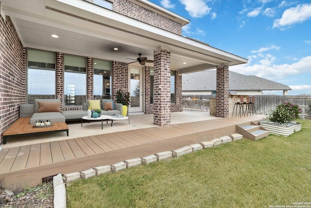 wooden terrace with ceiling fan, exterior bar, outdoor lounge area, and a yard