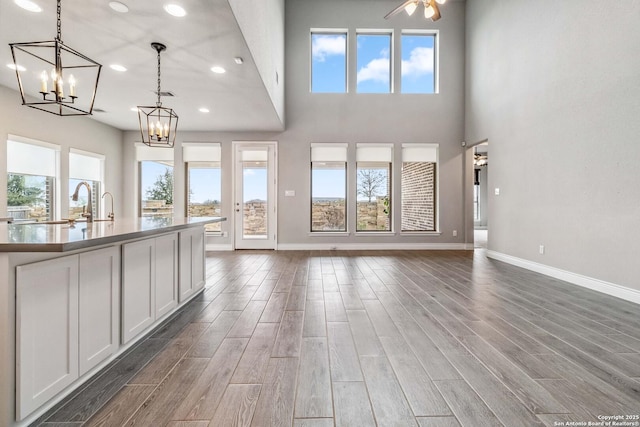 unfurnished living room with ceiling fan with notable chandelier and sink