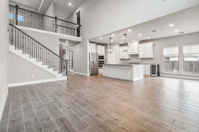 unfurnished living room with wine cooler, a high ceiling, and sink