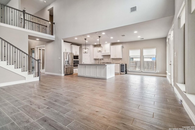 unfurnished living room with sink, a high ceiling, and beverage cooler