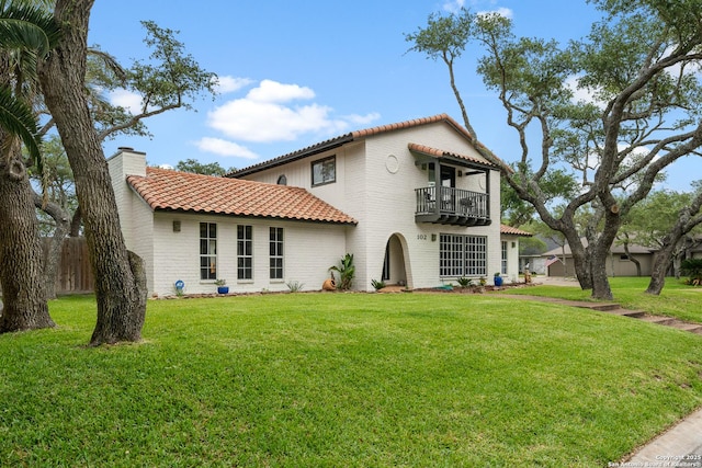 rear view of property featuring a balcony and a yard