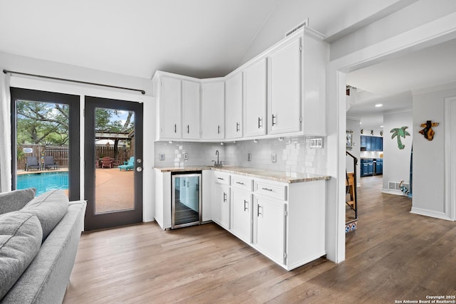 kitchen featuring light hardwood / wood-style floors, white cabinets, and wine cooler