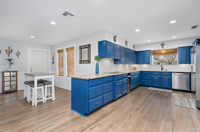 kitchen featuring light hardwood / wood-style floors, blue cabinetry, backsplash, stainless steel dishwasher, and sink