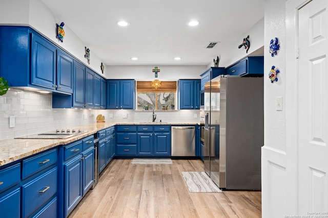 kitchen featuring light stone countertops, appliances with stainless steel finishes, sink, and blue cabinetry