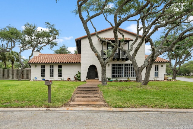 mediterranean / spanish house with a front lawn and a balcony