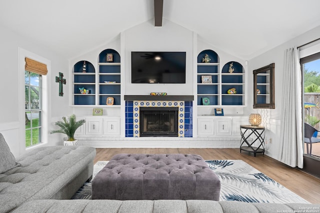 living room with vaulted ceiling with beams, a fireplace, wood-type flooring, and built in shelves