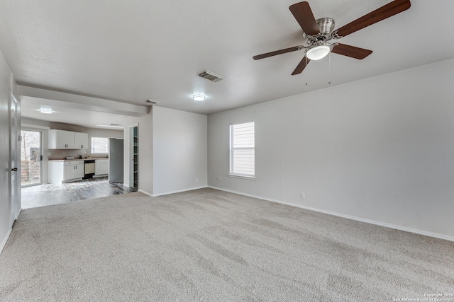 unfurnished living room with light carpet, ceiling fan, and plenty of natural light