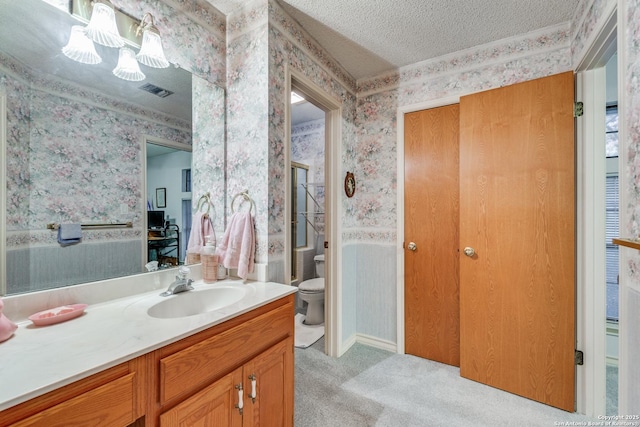 bathroom featuring toilet, a textured ceiling, and vanity