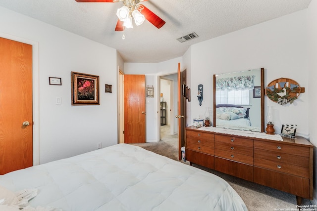 bedroom with ceiling fan, light colored carpet, and a textured ceiling