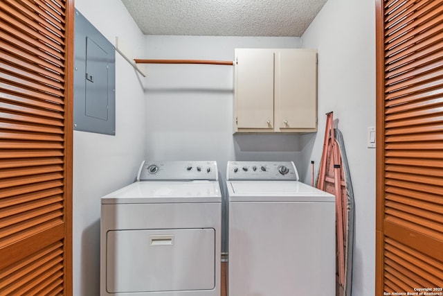 clothes washing area featuring independent washer and dryer, electric panel, a textured ceiling, and cabinets