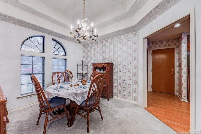 dining room with hardwood / wood-style flooring, a raised ceiling, and a notable chandelier