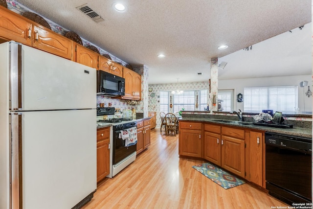 kitchen with black appliances, light wood-type flooring, sink, and a textured ceiling