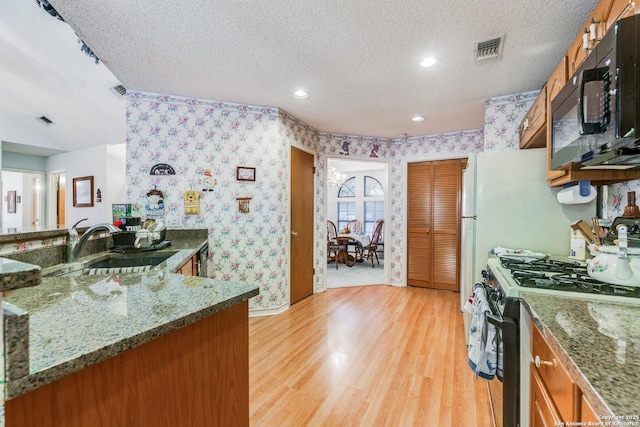 kitchen with a textured ceiling, range with gas stovetop, light hardwood / wood-style flooring, and sink