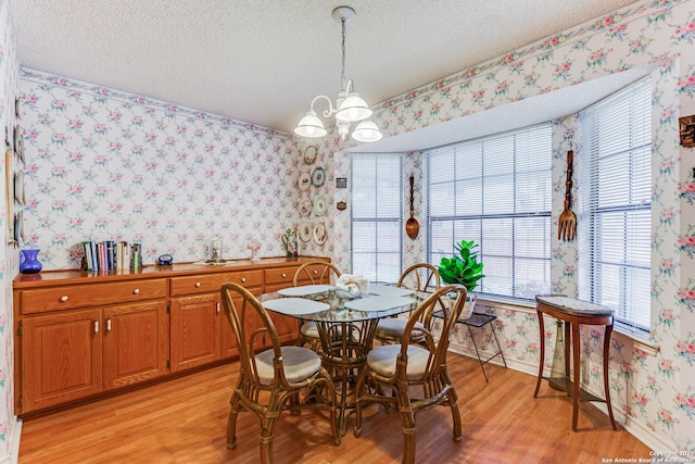 dining space with a notable chandelier, a textured ceiling, and light hardwood / wood-style floors