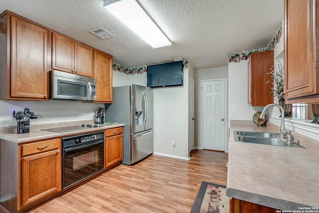 kitchen with a textured ceiling, sink, light hardwood / wood-style floors, and black appliances