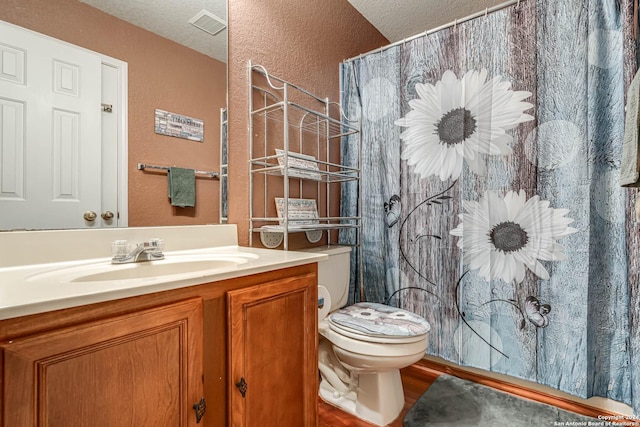 bathroom with a textured ceiling, toilet, and vanity