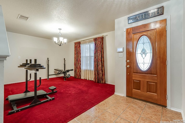 tiled foyer with a textured ceiling and an inviting chandelier