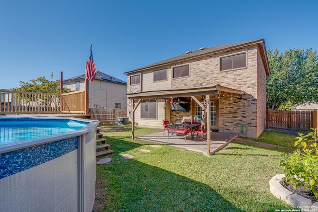 rear view of property with a lawn, cooling unit, a patio, and a fenced in pool