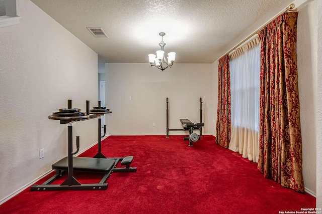 exercise area featuring plenty of natural light, a textured ceiling, a chandelier, and carpet flooring