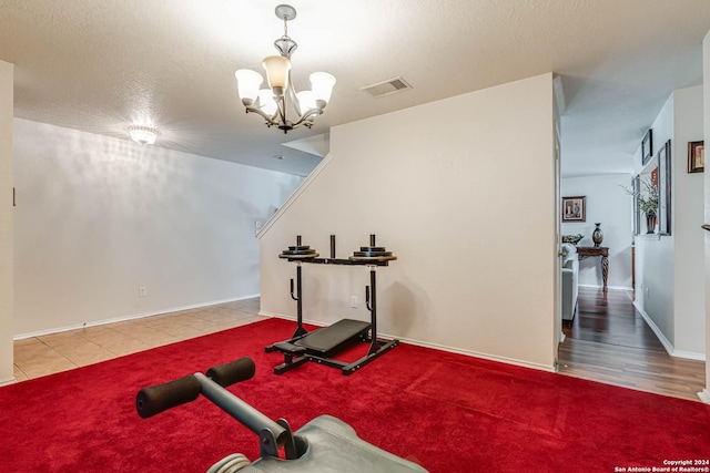 exercise area with a notable chandelier and a textured ceiling