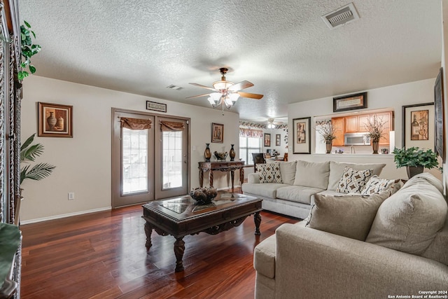 living room with a textured ceiling, ceiling fan, and dark hardwood / wood-style floors