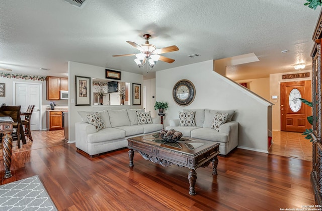 living room featuring ceiling fan, dark wood-type flooring, and a textured ceiling