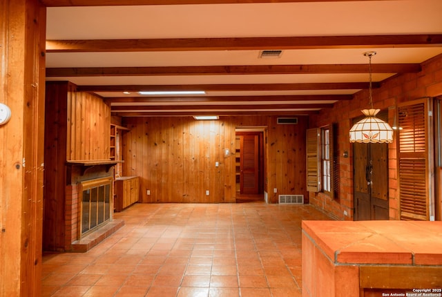 unfurnished living room with beamed ceiling, a fireplace, and wooden walls