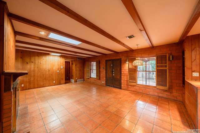 unfurnished living room featuring beam ceiling, wooden walls, and light tile patterned flooring