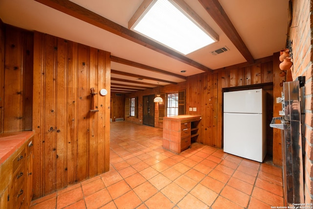 kitchen with white refrigerator, wooden walls, and beamed ceiling