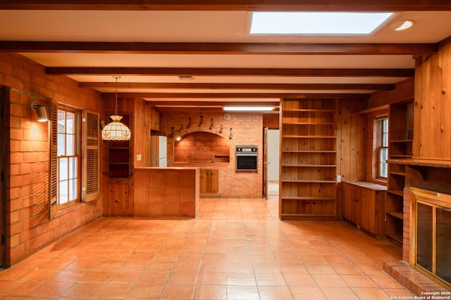 kitchen with hanging light fixtures, oven, beamed ceiling, and white fridge