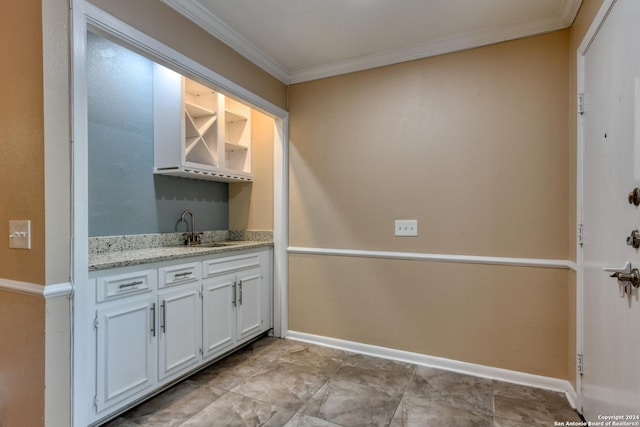 bar with crown molding, white cabinets, light stone counters, and sink