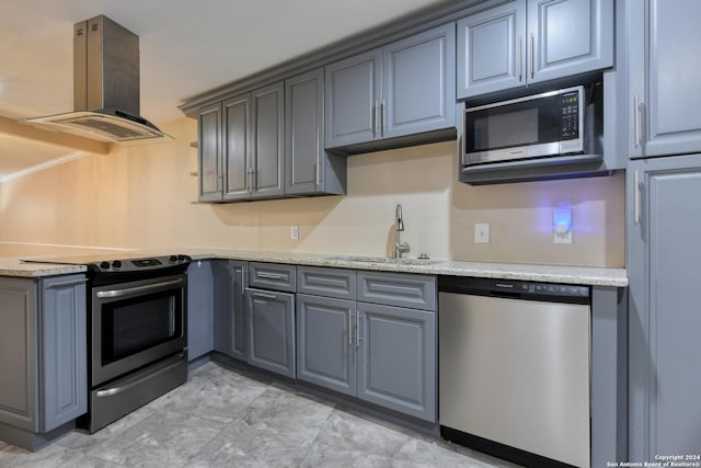 kitchen featuring gray cabinets, sink, appliances with stainless steel finishes, island range hood, and light stone counters