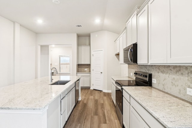 kitchen with sink, white cabinetry, a center island with sink, appliances with stainless steel finishes, and light stone countertops