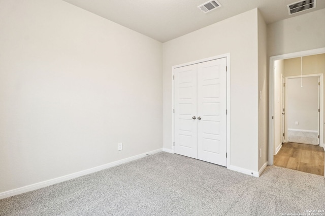 unfurnished bedroom featuring light carpet and a closet