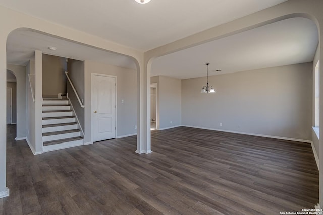 unfurnished living room featuring dark wood-type flooring and an inviting chandelier