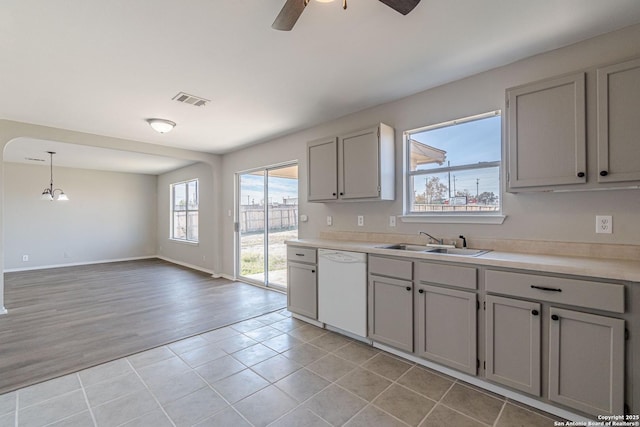 kitchen with gray cabinetry, white dishwasher, hanging light fixtures, ceiling fan with notable chandelier, and sink