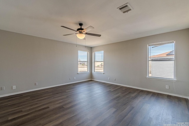 empty room featuring ceiling fan, dark wood-type flooring, and a healthy amount of sunlight