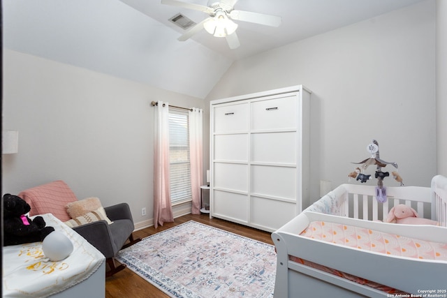 bedroom featuring ceiling fan, dark hardwood / wood-style flooring, lofted ceiling, and a nursery area