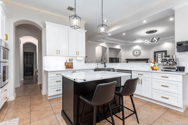 kitchen featuring kitchen peninsula, a kitchen breakfast bar, a kitchen island, white cabinets, and sink