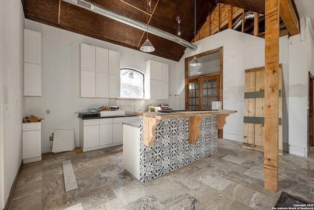 kitchen featuring high vaulted ceiling, white cabinetry, and a kitchen island