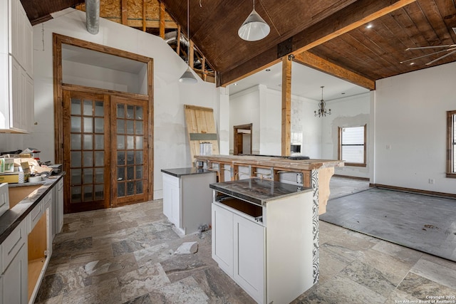 kitchen featuring pendant lighting, white cabinets, a center island, wood ceiling, and a notable chandelier