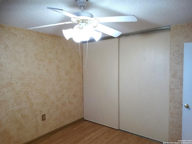 empty room featuring hardwood / wood-style flooring, a textured ceiling, and ceiling fan