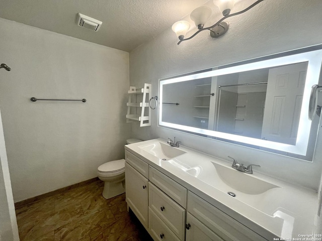 bathroom with a textured ceiling, toilet, vanity, and walk in shower